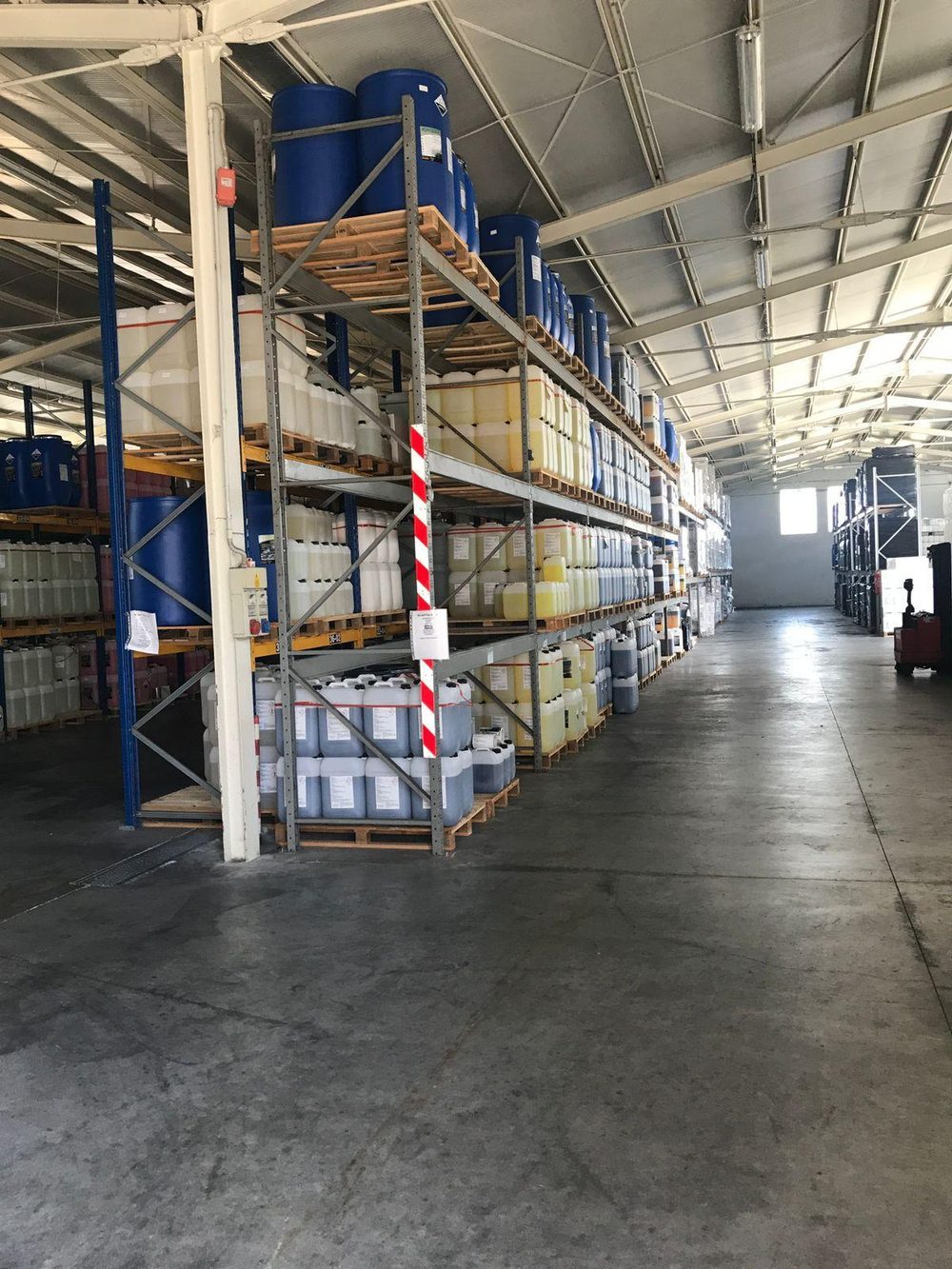 Entrepôt industriel équipé de rayonnages à palettes ARCOSTE stockant fûts et bidons, avec allée de circulation dégagée
